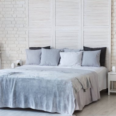 Yatak odasının içi açık renkli. Yastıklı ve örtülü bir yatak var. Uyumak için harika bir yer. Yastığa odaklan.