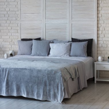 Yatak odasının içi açık renkli. Yastıklı ve örtülü bir yatak var. Uyumak için harika bir yer.