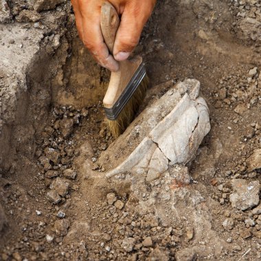Profesyonel arkeolojik kazılar, arkeologlar, toprakta özel aletler bulunan antik bir kil eserini kazıyorlar.