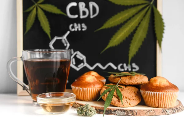 Muffins und Kekse mit CBD-Cannabis und Blattgarnitur. Arzneimittel. Medizinische Marihuana-Behandlung für den menschlichen Konsum. Gegen eine Tafel mit CBD-Hanfform. Stockbild