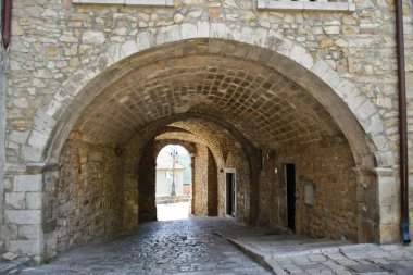 A narrow street between the old houses of Pietragalla, a village in the Basilicata region, Italy.