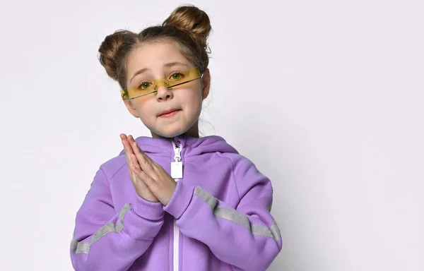 Klein kleuter meisje in een warme blauwe sport overalls op een grijze achtergrond. Schattig meisje dat naar de camera kijkt. Sportmode voor kinderen. — Stockfoto