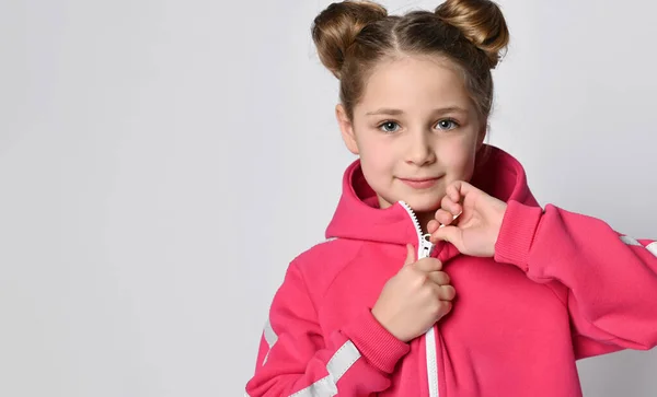 Schattig meisje in een warme sweater trui met een capuchon, demonstreert de rits, knoopt de trui los. Hot roze kids hoodie — Stockfoto