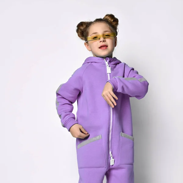 Piccola bambina in una calda tuta sportiva blu su uno sfondo grigio. Carina la ragazzina che guarda la telecamera. Moda sportiva per bambini. — Foto Stock