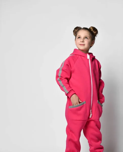Waist-length portrait of a stylish girl in a pink sports suit with reflective stripes, looks to the side. stylish cotton tracksuit, pajamas with a hood, a fashion model for children — Foto Stock