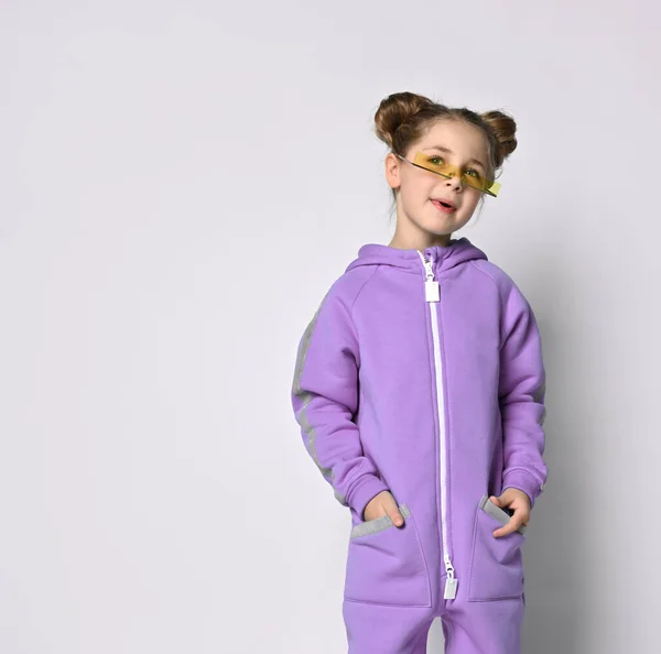 Piccola bambina in una calda tuta sportiva blu su uno sfondo grigio. Carina la ragazzina che guarda la telecamera. Moda sportiva per bambini. — Foto Stock