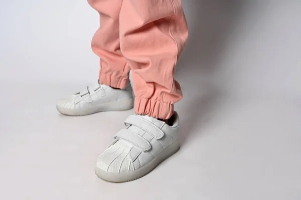 Patas de niño para mujer en cuero zapatillas blancas de moda en pantalones rosas con estilo con una banda elástica. Traje casual de moda. Detalles cotidianos. Moda callejera. —  Fotos de Stock