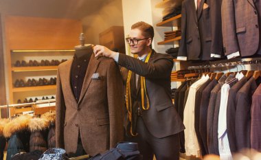 Elbise mağazasında takım elbise dikerken bir terzi portresi. Konsept: Moda, terzilik, dükkan.