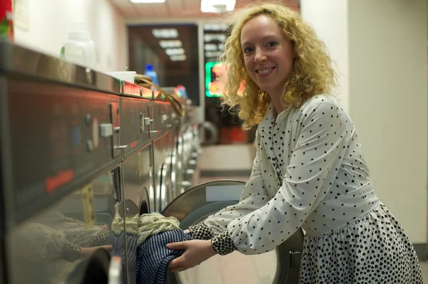 Laundromat girl inserting clothes — Stock Photo, Image