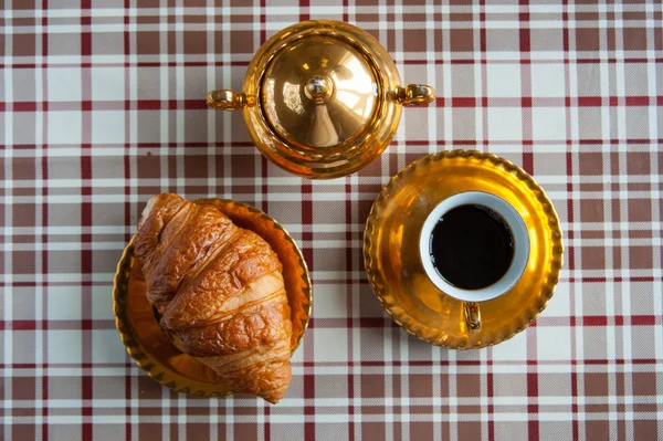 Xícara de ouro de café, tigela de açúcar e croissant — Fotografia de Stock