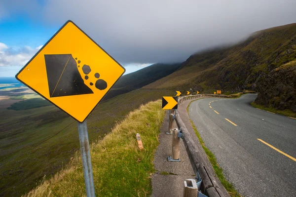 Steinschlag-Warnschild auf kurvenreicher Straße — Stockfoto