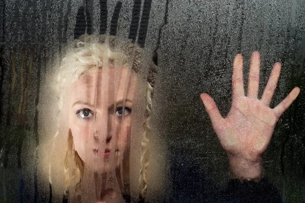 Sad woman looking through condensation window — Stock Photo, Image