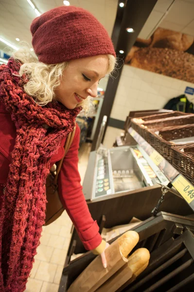 Jonge vrouw kopen stokbrood — Stockfoto