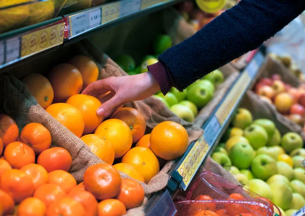 Het kiezen van een oranje in supermarkt — Stockfoto