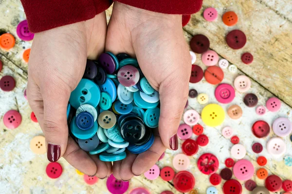 Sosteniendo un puñado de botones de costura de colores — Foto de Stock