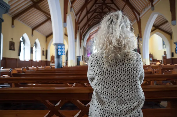 Donna che prega in chiesa da dietro — Foto Stock