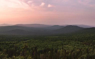 Dağ zirvelerinin fotoğrafları. Arka planda güzel bir mor gökyüzü. Açık hava manzarası, dağın tepesindeki yeşil orman. Yaz manzarası.