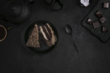 Siyah tabakta kek parçaları, koyu arkaplanda şekerli çay. Üst görünüm