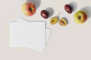 Mockup of blank white sheets of paper with fruits. Sunny summer day, long hard shadows. Flat lay.