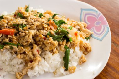 ahşap bir masa üzerinde beyaz bir tabakta Fesleğenli kızarmış pilav.