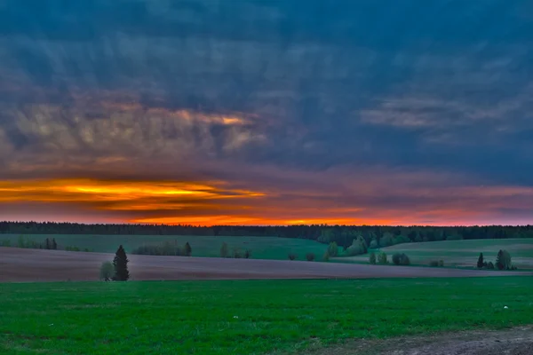 Farbenfrohe Morgendämmerung über Feldern mit ungewöhnlichen Wolken lizenzfreie Stockfotos