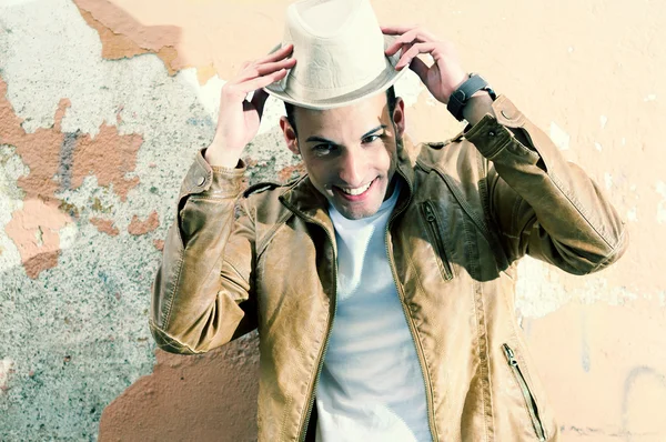 Atractivo joven sonriendo con un sombrero en el fondo urbano — Foto de Stock