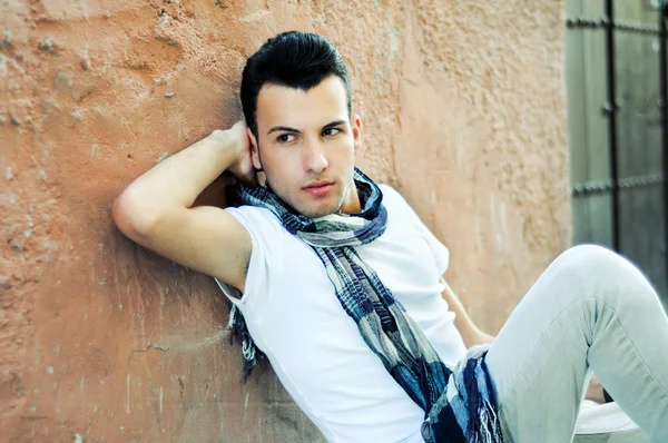 Retrato de un joven guapo, modelo de moda, con peluquín en el fondo urbano — Foto de Stock