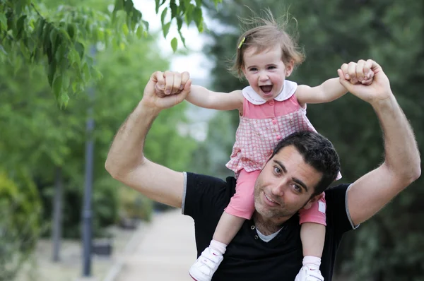 Little girl walking on the shoulders of her father — Stock Photo, Image