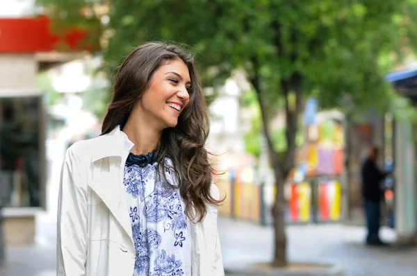 Retrato de una hermosa joven sonriendo en el fondo urbano —  Fotos de Stock