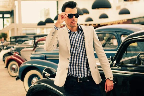 Attractive man wearing jacket and shirt with old cars Stock Image