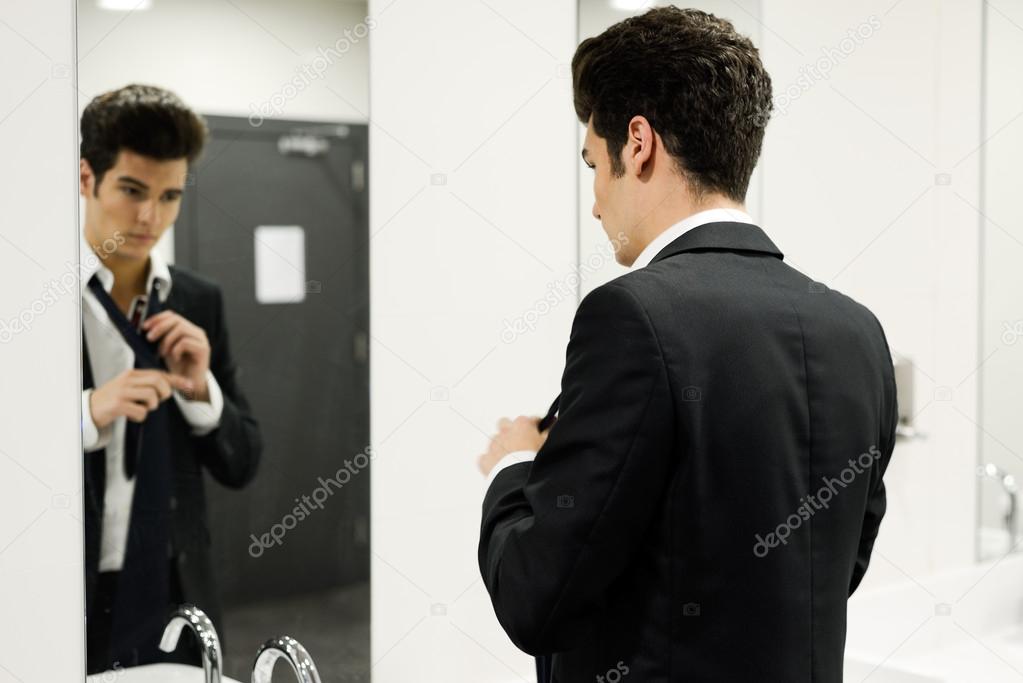 Man getting dressed in a public restroom with mirror