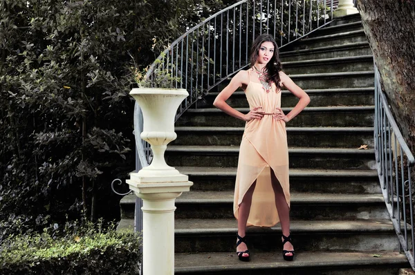 Retrato de una hermosa joven, modelo de moda, en una escalera de jardín — Foto de Stock
