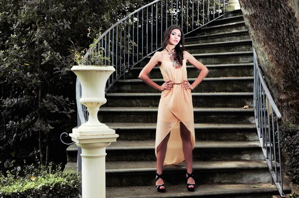 Portrait of a beautiful young woman, model of fashion, in a garden stairs — Stock Photo, Image