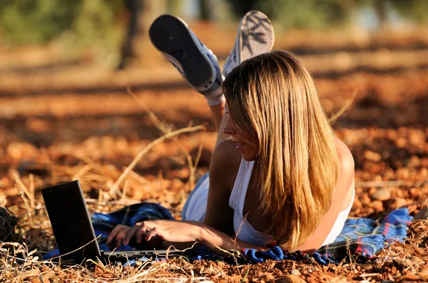 Ragazza con un computer portatile in un campo in autunno — Foto Stock