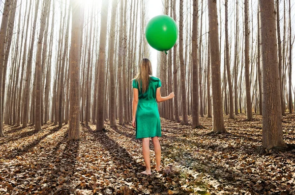 Schönes blondes Mädchen, grün gekleidet, steht im Wald — Stockfoto