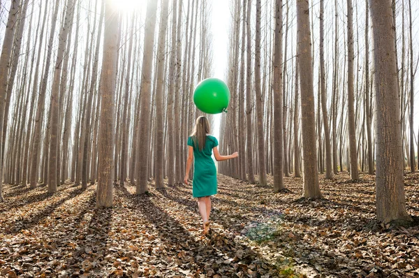 Menina loira bonita, vestida de verde, andando na floresta — Fotografia de Stock