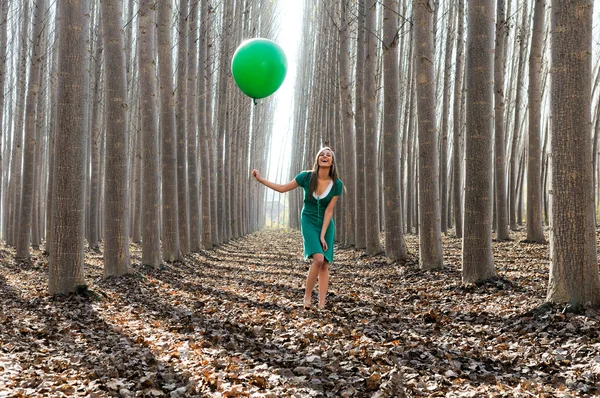 Menina loira bonita, vestida de verde, rindo na floresta — Fotografia de Stock