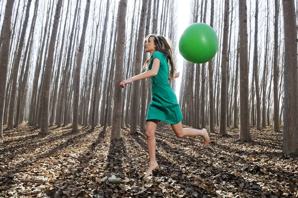 Menina loira bonita, vestida de verde, saltando para a floresta — Fotografia de Stock