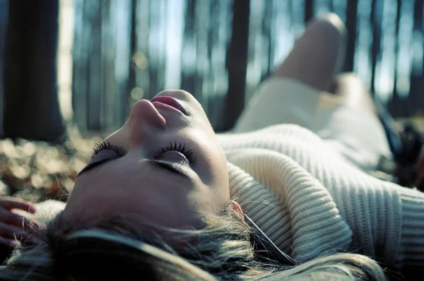 Menina loira bonita deitada em folhas em uma floresta de álamos — Fotografia de Stock