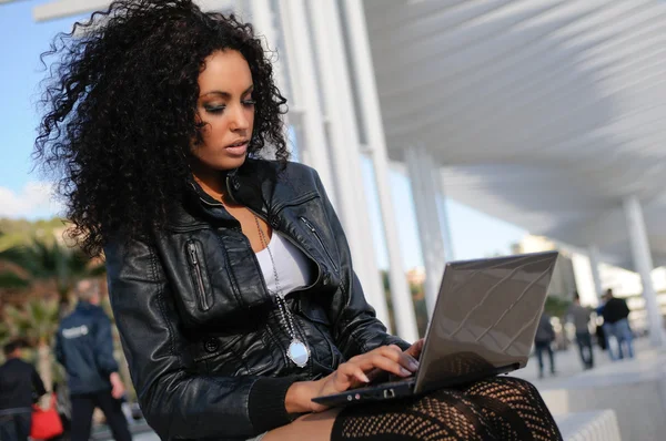 Felice rilassato ragazza africana utilizzando un computer portatile in strada — Foto Stock