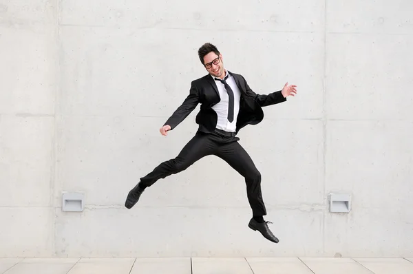 Jeune homme d'affaires beau avec des lunettes sautant dans la rue — Photo