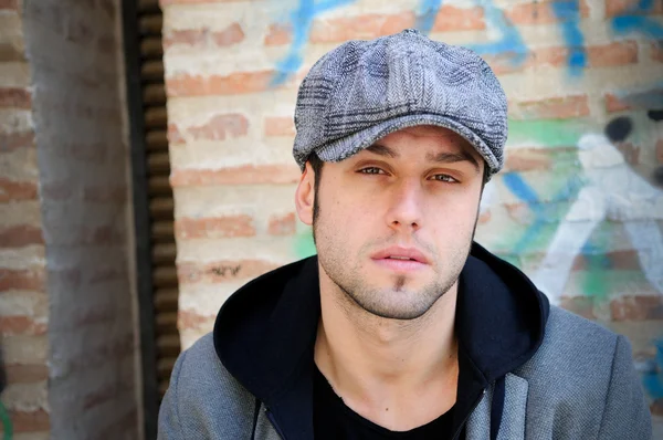 Portrait d'un bel homme en fond urbain portant une casquette rétro — Photo