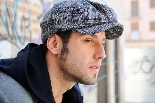 Portrait of handsome man in urban background wearing a retro cap — Stock Photo, Image