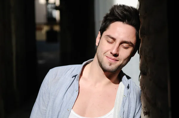 Retrato de joven hombre guapo en el fondo urbano con ojos clo — Foto de Stock