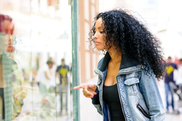 Portrait of an attractive black woman, afro hairstyle, looking at the shop window — Stock Photo, Image