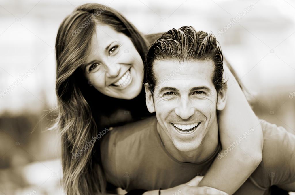 Portrait of smiling young man piggybacking his pretty girlfriend in the park