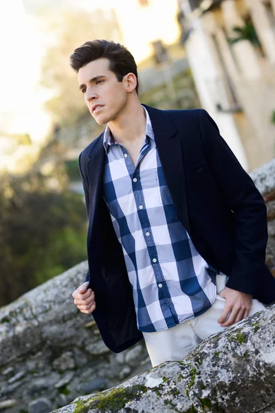 Hombre guapo con peinado moderno sonriendo en el fondo urbano —  Fotos de Stock