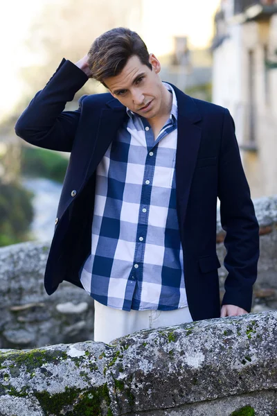 Hombre guapo con peinado moderno sonriendo en el fondo urbano —  Fotos de Stock