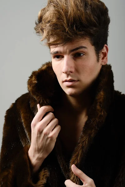 Attractive young man wearing fur coat with modern hairstyle — Stock Photo, Image
