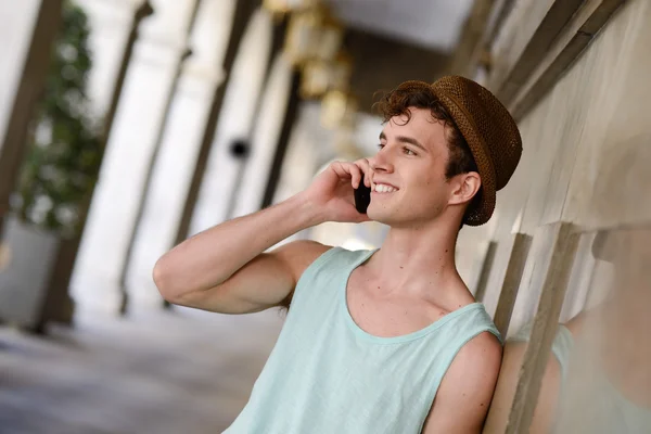 Attractive young man wearing hat talking on the mobile phone — Stock Photo, Image